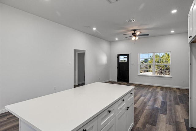 kitchen with white cabinets, dark hardwood / wood-style flooring, a center island, and ceiling fan