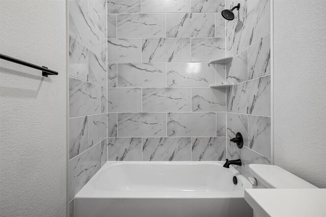 bathroom with tiled shower / bath combo and toilet