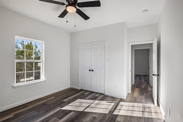 unfurnished bedroom featuring ceiling fan, dark hardwood / wood-style floors, and a closet