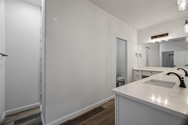 bathroom with hardwood / wood-style floors, vanity, and toilet