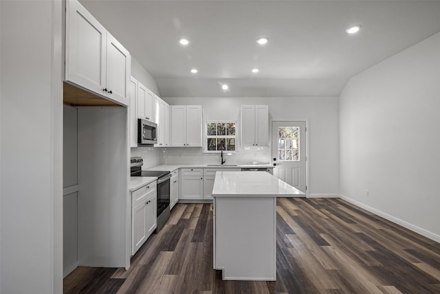 kitchen with white cabinets, dark hardwood / wood-style floors, a kitchen island, and appliances with stainless steel finishes