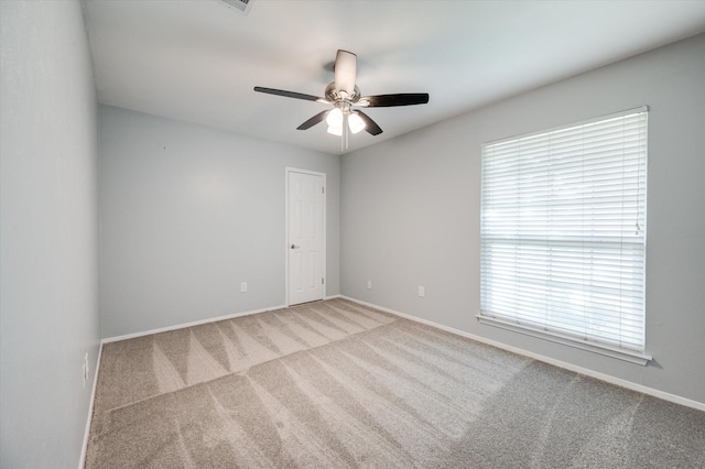 carpeted empty room featuring ceiling fan and plenty of natural light