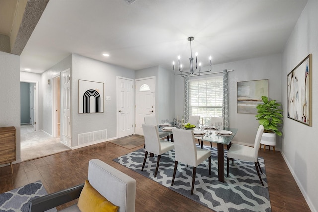 dining space featuring dark hardwood / wood-style floors and an inviting chandelier