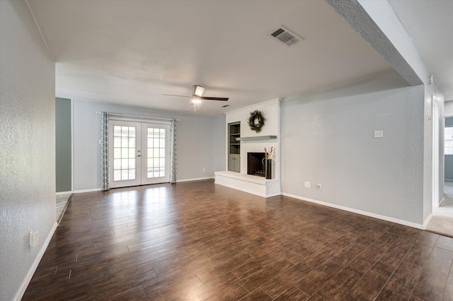 unfurnished living room featuring built in shelves, french doors, dark hardwood / wood-style floors, and ceiling fan