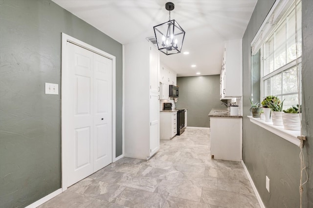 kitchen featuring a chandelier, white cabinetry, hanging light fixtures, and black appliances