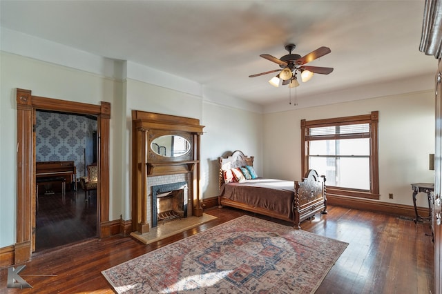 bedroom with ceiling fan, a premium fireplace, and dark hardwood / wood-style floors