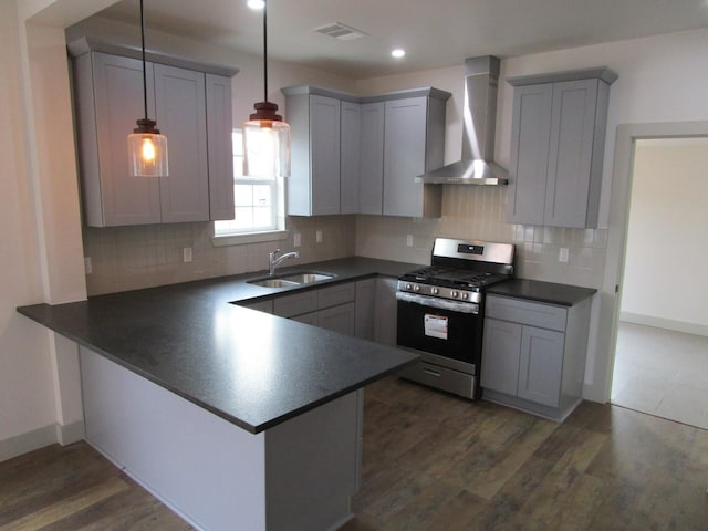 kitchen with wall chimney range hood, sink, stainless steel gas range oven, decorative light fixtures, and kitchen peninsula