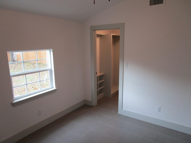 tiled empty room with lofted ceiling