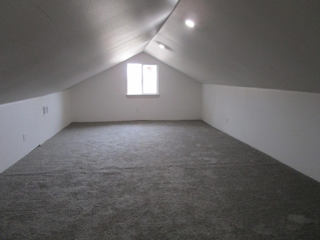 bonus room with vaulted ceiling and carpet flooring