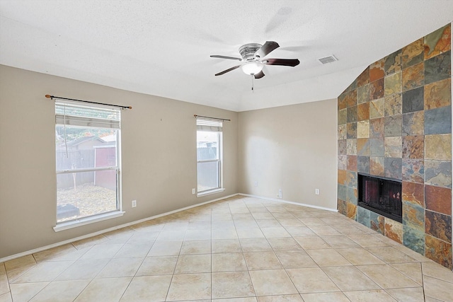 unfurnished living room featuring light tile patterned floors, ceiling fan, lofted ceiling, a textured ceiling, and a tile fireplace