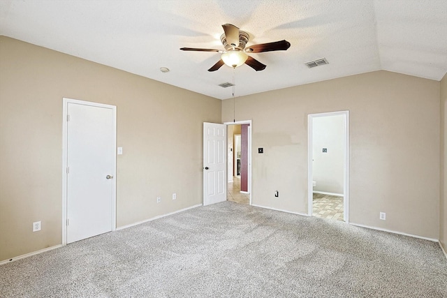 carpeted empty room featuring vaulted ceiling, ceiling fan, and a textured ceiling