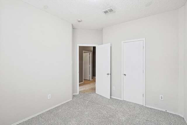 unfurnished bedroom with a textured ceiling and light carpet