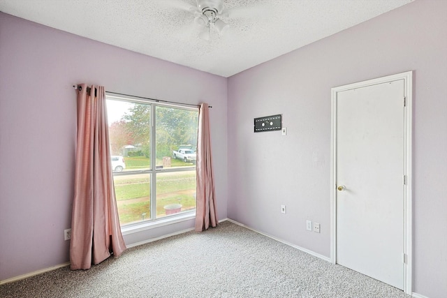 empty room with a textured ceiling, ceiling fan, and carpet flooring