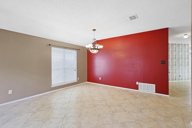 spare room with light tile patterned floors, a notable chandelier, and a textured ceiling