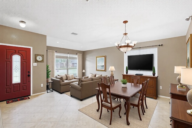 dining area with a textured ceiling, light tile patterned floors, and a chandelier