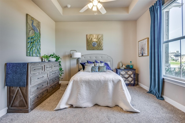 bedroom with carpet flooring, ceiling fan, and a tray ceiling