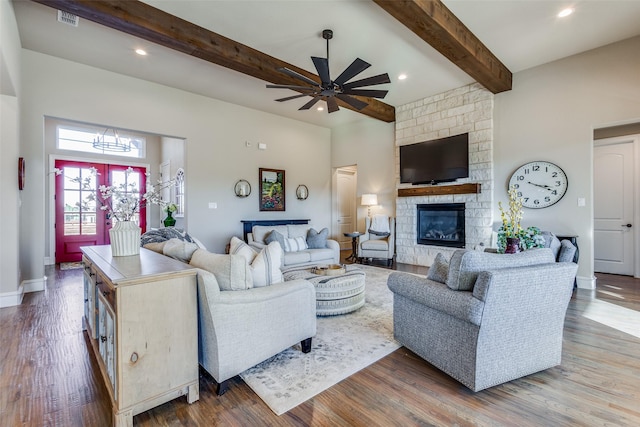 living room with a fireplace, beam ceiling, ceiling fan with notable chandelier, and hardwood / wood-style floors