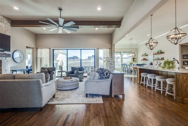 living room featuring beamed ceiling, ceiling fan, a stone fireplace, and dark hardwood / wood-style flooring