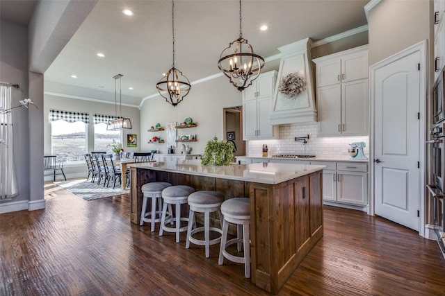 kitchen with a notable chandelier, backsplash, a center island, and white cabinets