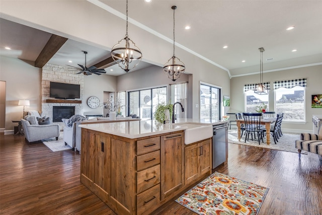 kitchen with ceiling fan with notable chandelier, sink, hanging light fixtures, a fireplace, and an island with sink