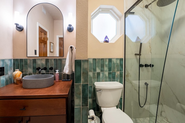 bathroom with vanity, toilet, a shower with door, and tile walls