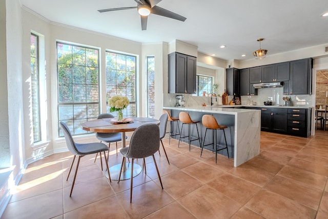 kitchen with crown molding, pendant lighting, decorative backsplash, a breakfast bar, and light tile patterned floors