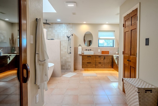 bathroom featuring tile patterned flooring, vanity, a tile shower, and tile walls