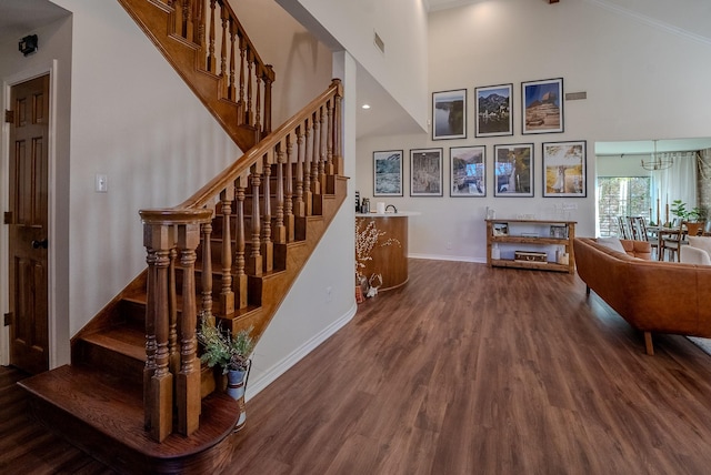 stairs featuring hardwood / wood-style floors, a notable chandelier, and high vaulted ceiling