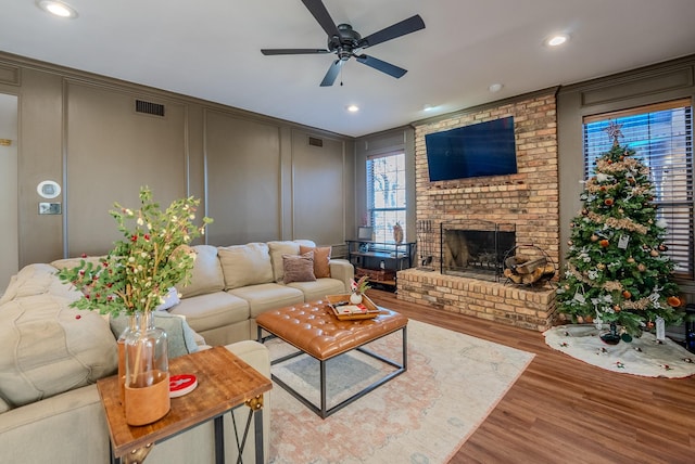 living room featuring ceiling fan, wood-type flooring, and a fireplace