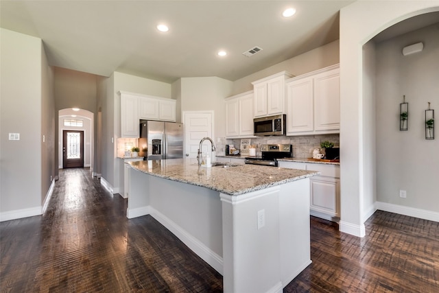 kitchen featuring white cabinetry, sink, dark wood-type flooring, stainless steel appliances, and a kitchen island with sink