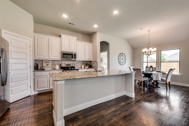 kitchen with white cabinets, dark hardwood / wood-style floors, appliances with stainless steel finishes, and tasteful backsplash