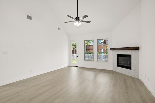 unfurnished living room featuring ceiling fan, a premium fireplace, high vaulted ceiling, and light wood-type flooring