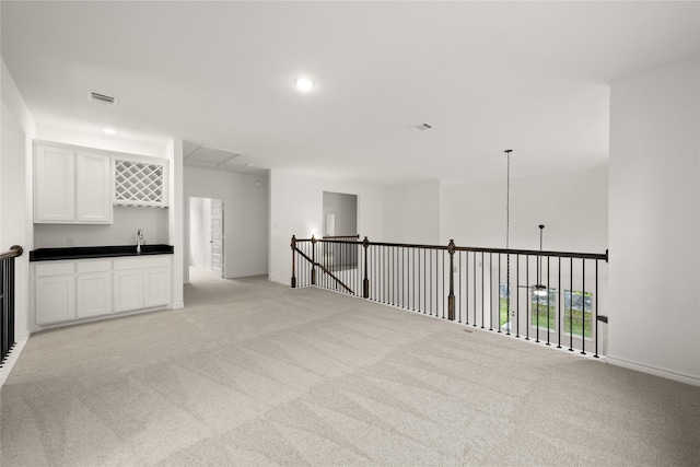 spare room featuring wet bar and light carpet