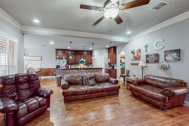 living room featuring ceiling fan, light wood-type flooring, crown molding, and wooden walls