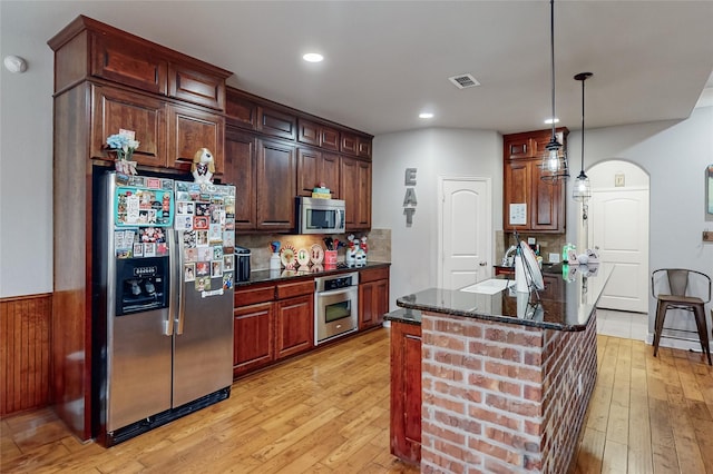 kitchen featuring appliances with stainless steel finishes, light wood-type flooring, hanging light fixtures, and sink