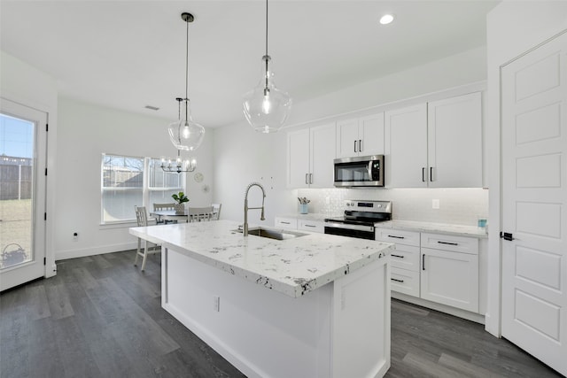 kitchen with stainless steel appliances, sink, pendant lighting, a center island with sink, and white cabinetry