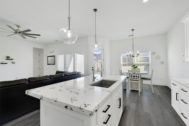 kitchen with a kitchen island with sink, dark wood-type flooring, white cabinets, sink, and decorative light fixtures