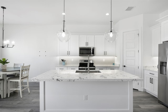 kitchen featuring appliances with stainless steel finishes, wood-type flooring, white cabinetry, hanging light fixtures, and an island with sink