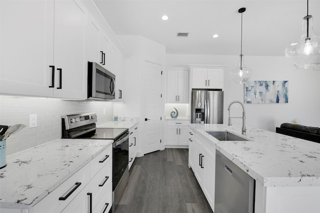 kitchen featuring sink, dark hardwood / wood-style floors, an island with sink, decorative light fixtures, and appliances with stainless steel finishes