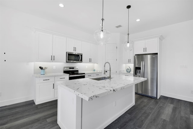 kitchen with dark wood-type flooring, hanging light fixtures, stainless steel appliances, an island with sink, and white cabinets