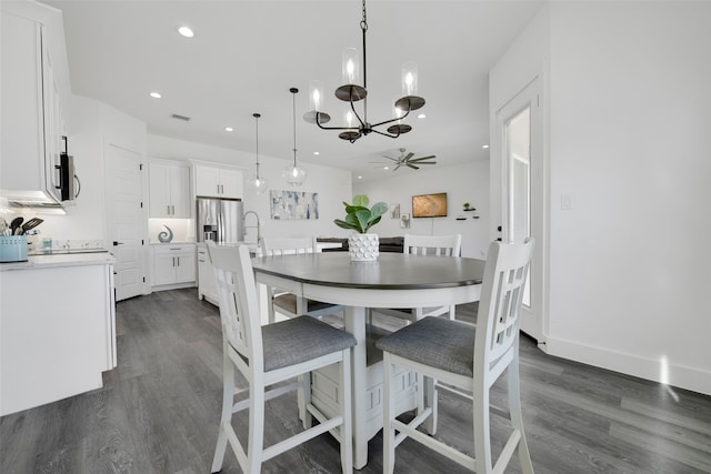 dining area with ceiling fan with notable chandelier, dark hardwood / wood-style flooring, and sink