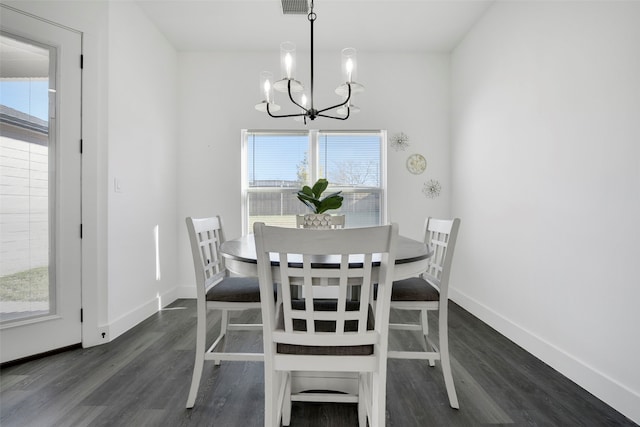 dining space with dark wood-type flooring and an inviting chandelier