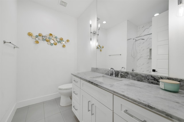 bathroom with tile patterned flooring, a tile shower, vanity, and toilet