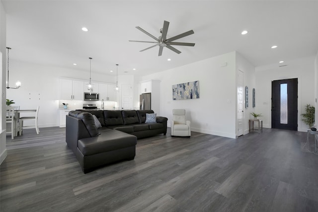 living room with ceiling fan, sink, and dark wood-type flooring