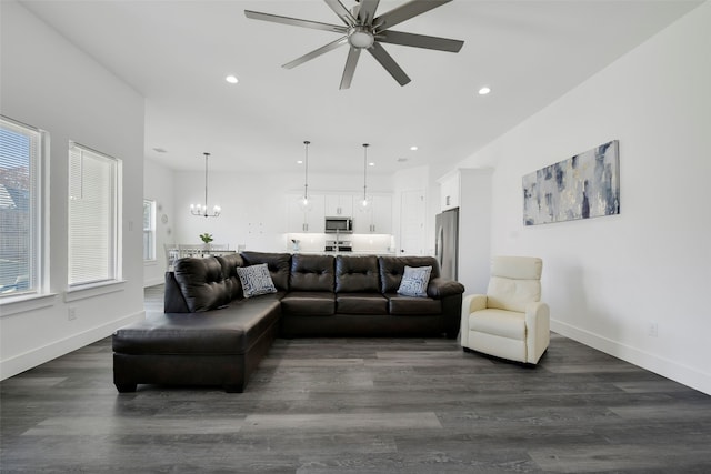 living room with ceiling fan with notable chandelier and dark hardwood / wood-style floors