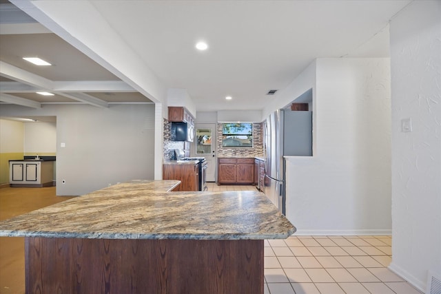 kitchen with beam ceiling, stainless steel appliances, kitchen peninsula, decorative backsplash, and light tile patterned flooring