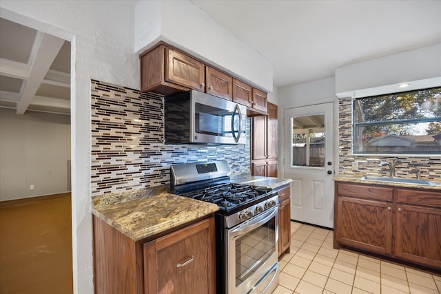 kitchen featuring sink, stainless steel appliances, coffered ceiling, tasteful backsplash, and light stone counters