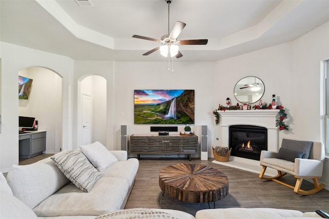 living room with a tray ceiling, ceiling fan, and dark hardwood / wood-style flooring