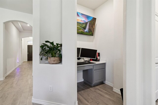 home office with built in desk and light wood-type flooring