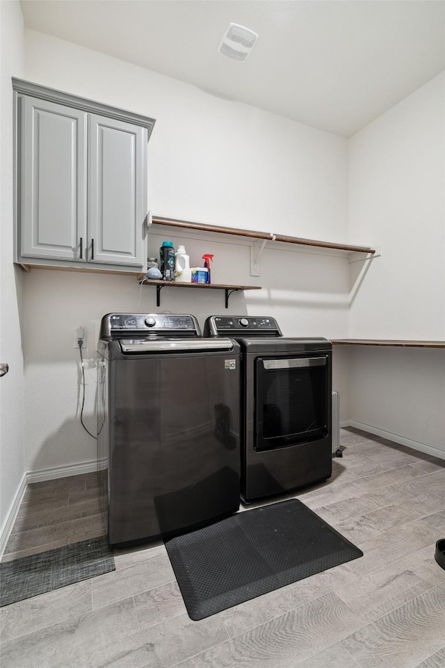 washroom with cabinets, light hardwood / wood-style floors, and washer and dryer